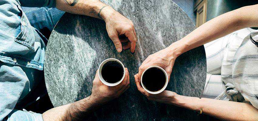 Two people sitting at a table with coffee cups.